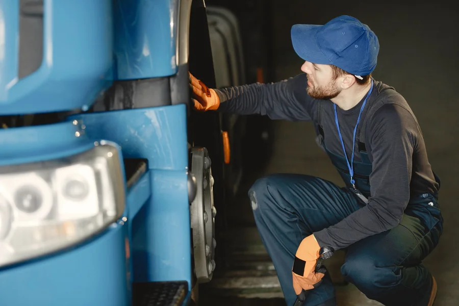 Mechanic inspecting tire on a commercial fleet vehicle at a service center
