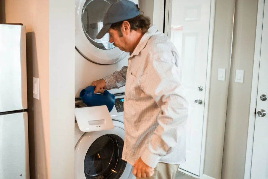 Scheduled Appliance Repair Technician servicing a washing machine after a predictive maintenance alert in a home laundry room