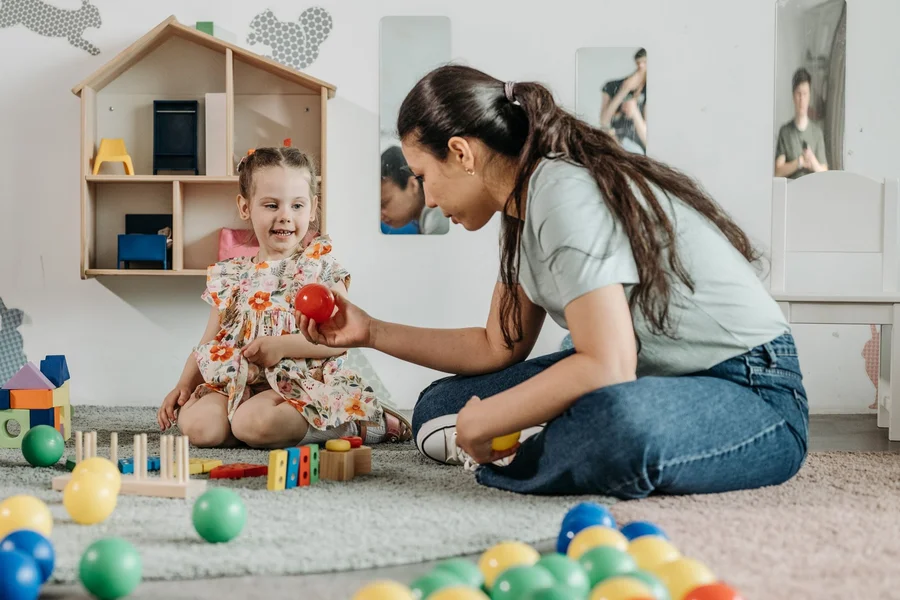 Childcare teacher supervising toddlers in a daycare classroom during activity time
