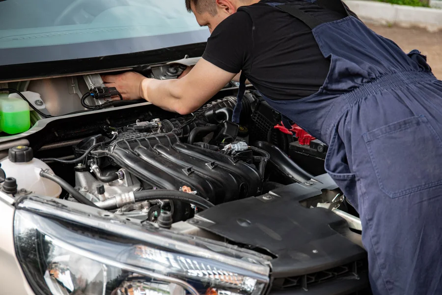 EV battery inspection by technician Technician inspecting an electric vehicle battery and engine bay for diagnostics