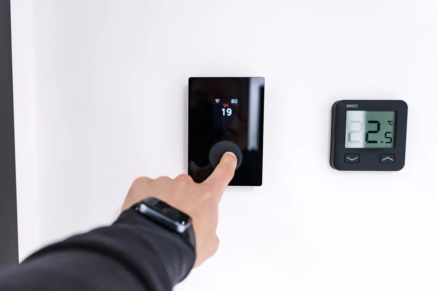 Smart thermostat AI monitoring Smart thermostat with digital display mounted on a home wall for AI climate monitoring