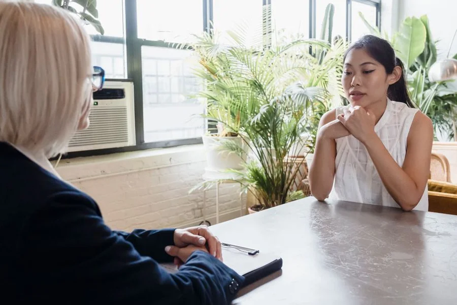 Two women in smart casual clothing talking across a table during an interview
