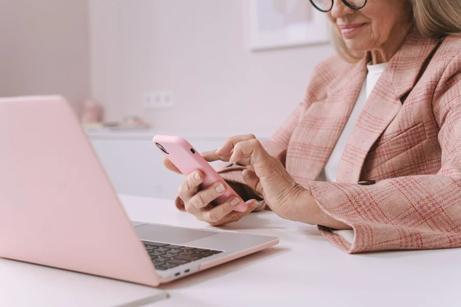 Choosing between AI agents Person checking tasks on a smartphone beside an open laptop