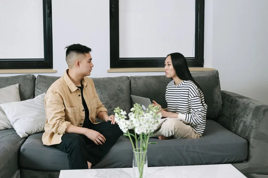 Two roommates having a serious conversation about money in their apartment living room
