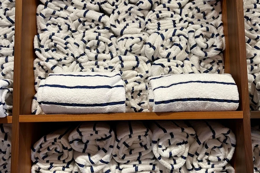 Fabric And Care Folded white cotton shirts on a shelf showing different fabric weights and weaves