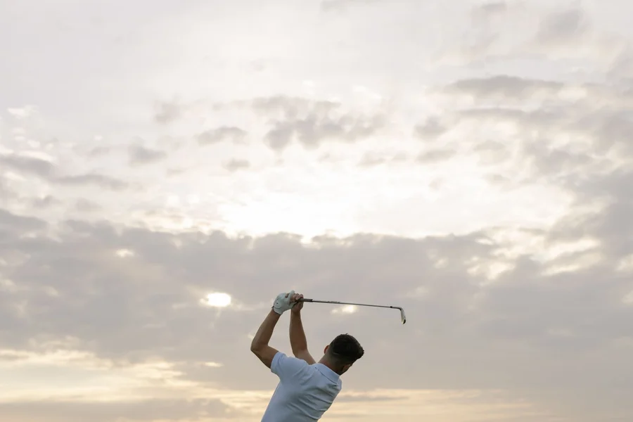 Sleeve length and the golf swing Golfer at the top of the backswing against a cloudy sky